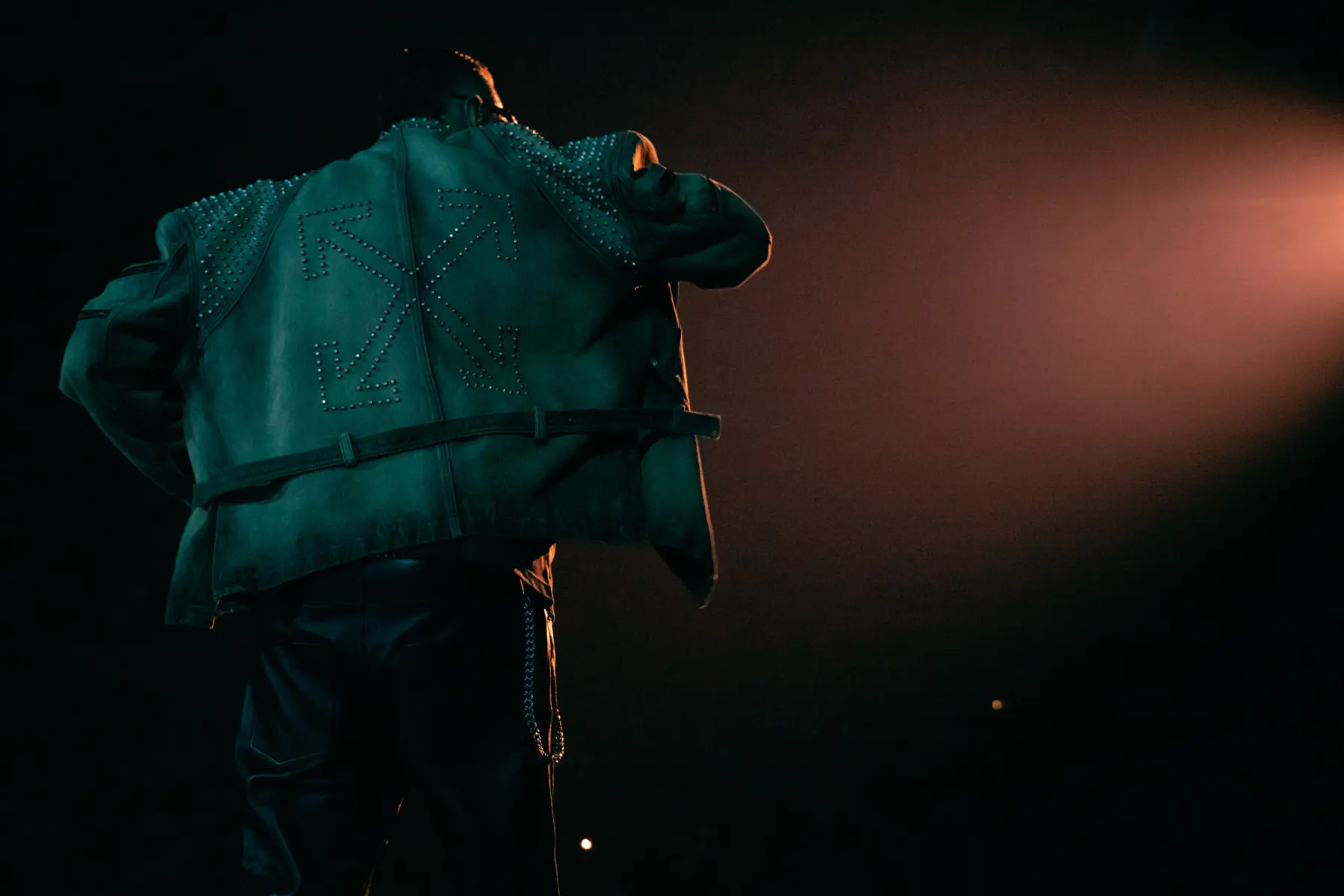 Marracash live, seen from behind in a studded jacket